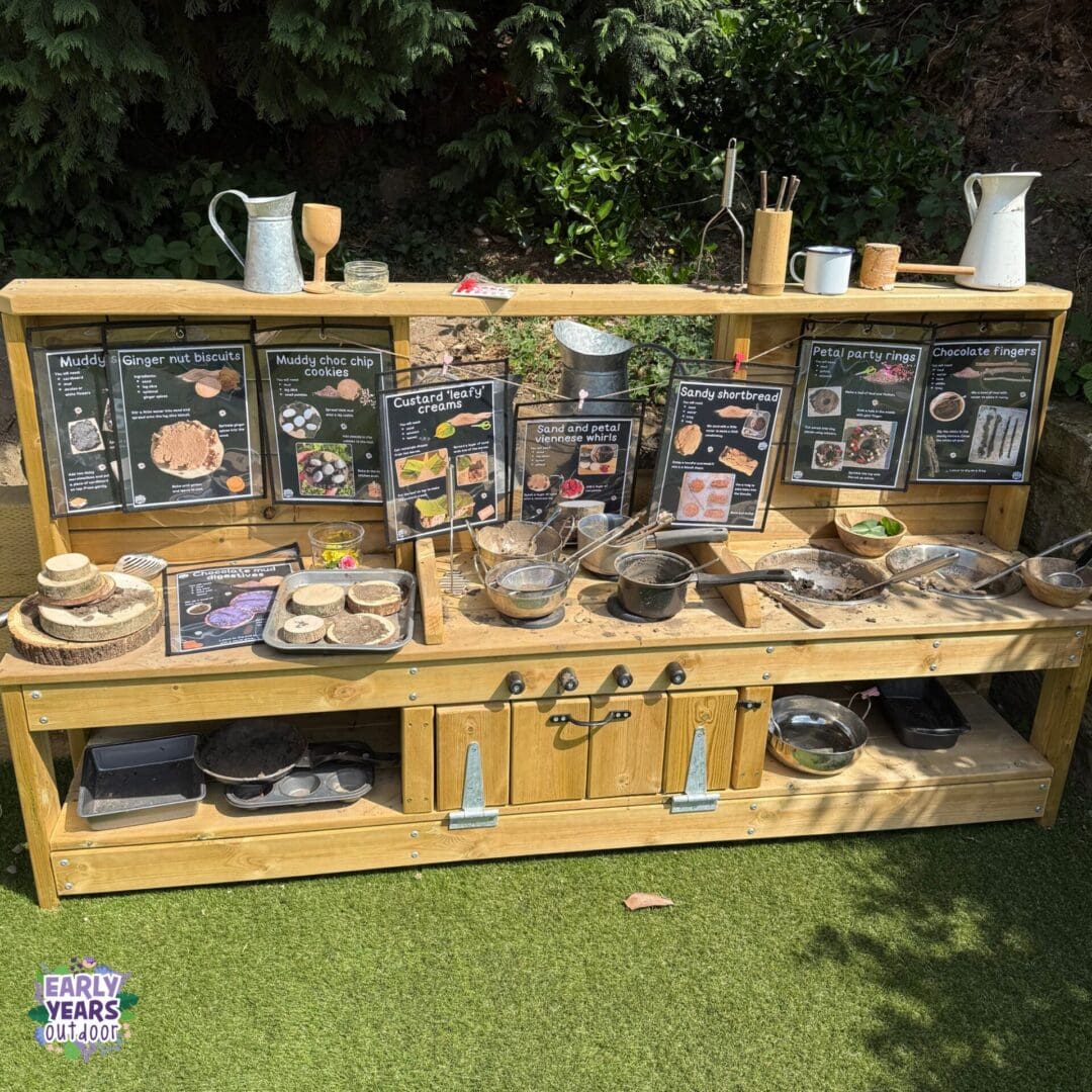 Muddy biscuits mud kitchen Muddy biscuit mud kitchen set up with recipes, log slices, trays, pans, utensils, nature and sticks
